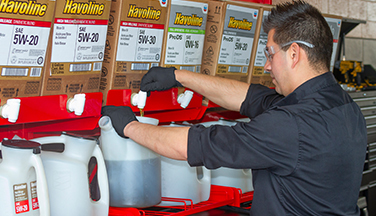 man pouring oil from Havoline PItPack rack